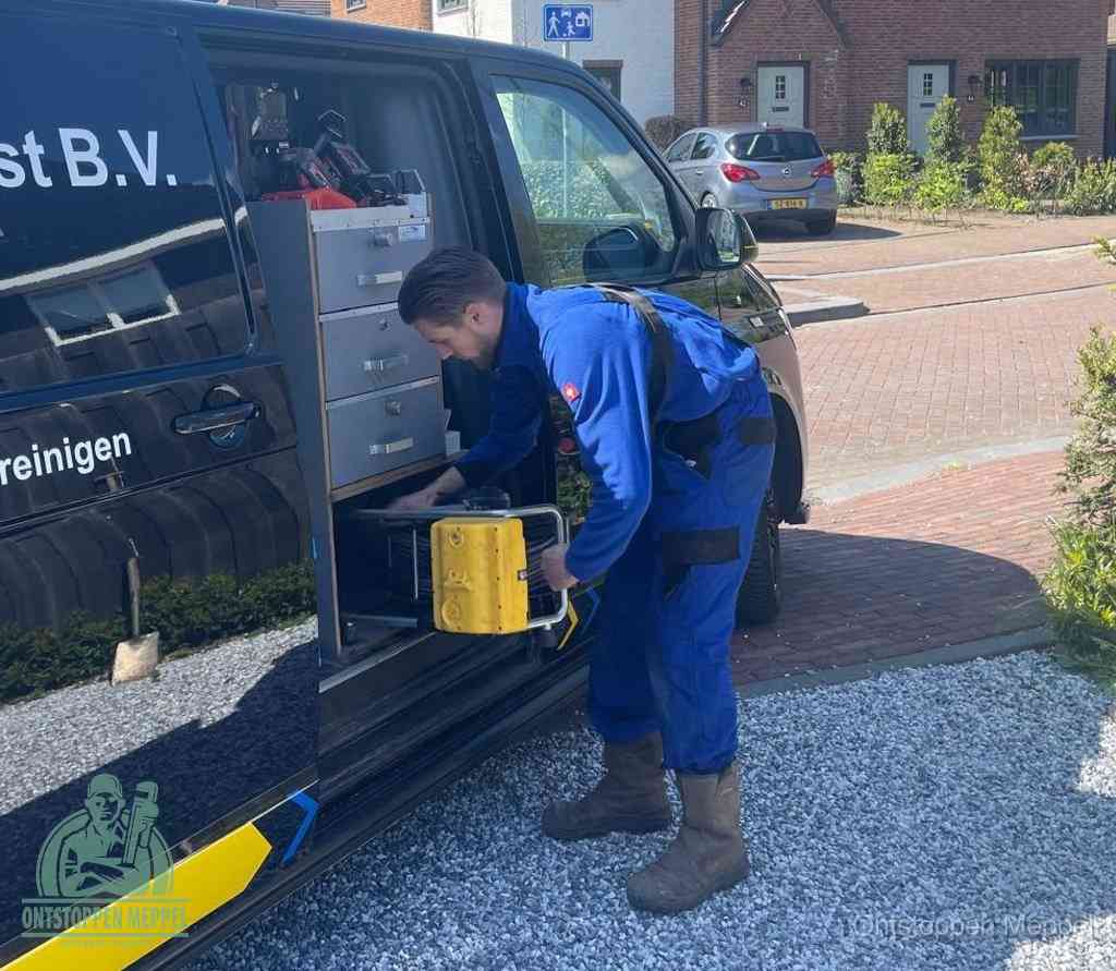Een monteur pakt buiten op de oprit gereedschap uit de bedrijfsbus, het moment om een professional in te schakelen voor een verstopte afvoer in Meppel