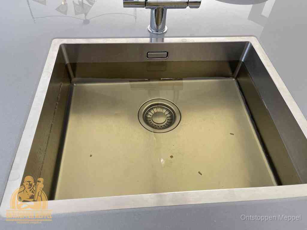 Stilstaand water in een rvs spoelbak dat niet wegloopt, een duidelijk signaal van een gootsteenverstopping in Meppel