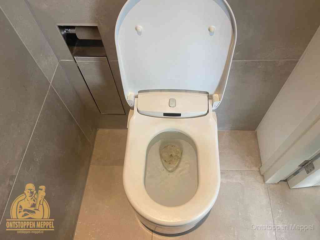 Een wit hangtoilet waarin een prop wc-papier op het water blijft drijven, een duidelijk signaal van een verstopte wc in Meppel