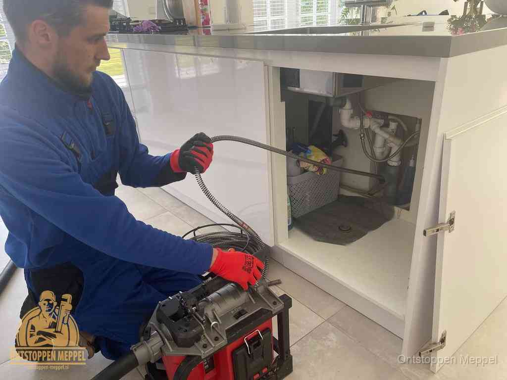 Een monteur reinigt de keukenafvoer grondig met een veermachine om terugkerende gootsteenverstoppingen te voorkomen in Meppel