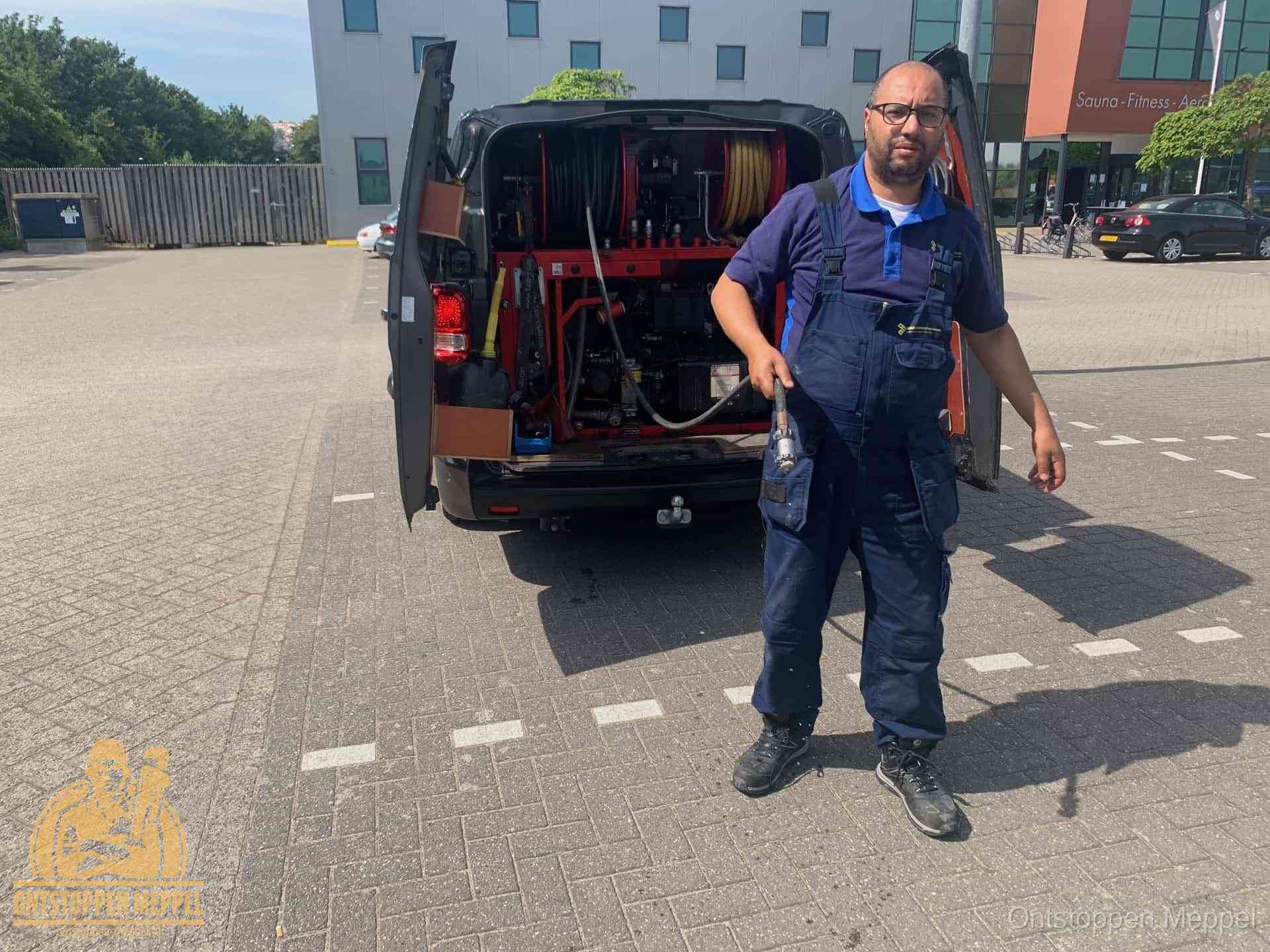 Een monteur bij zijn bestelbus met een hogedruk- en rioolreinigingsunit, klaar om de oorzaak van terugkerende wc-verstoppingen aan te pakken in Meppel Een monteur bij zijn bestelbus met een hogedruk- en rioolreinigingsunit, klaar om de oorzaak van terugkerende wc-verstoppingen aan te pakken in Meppel