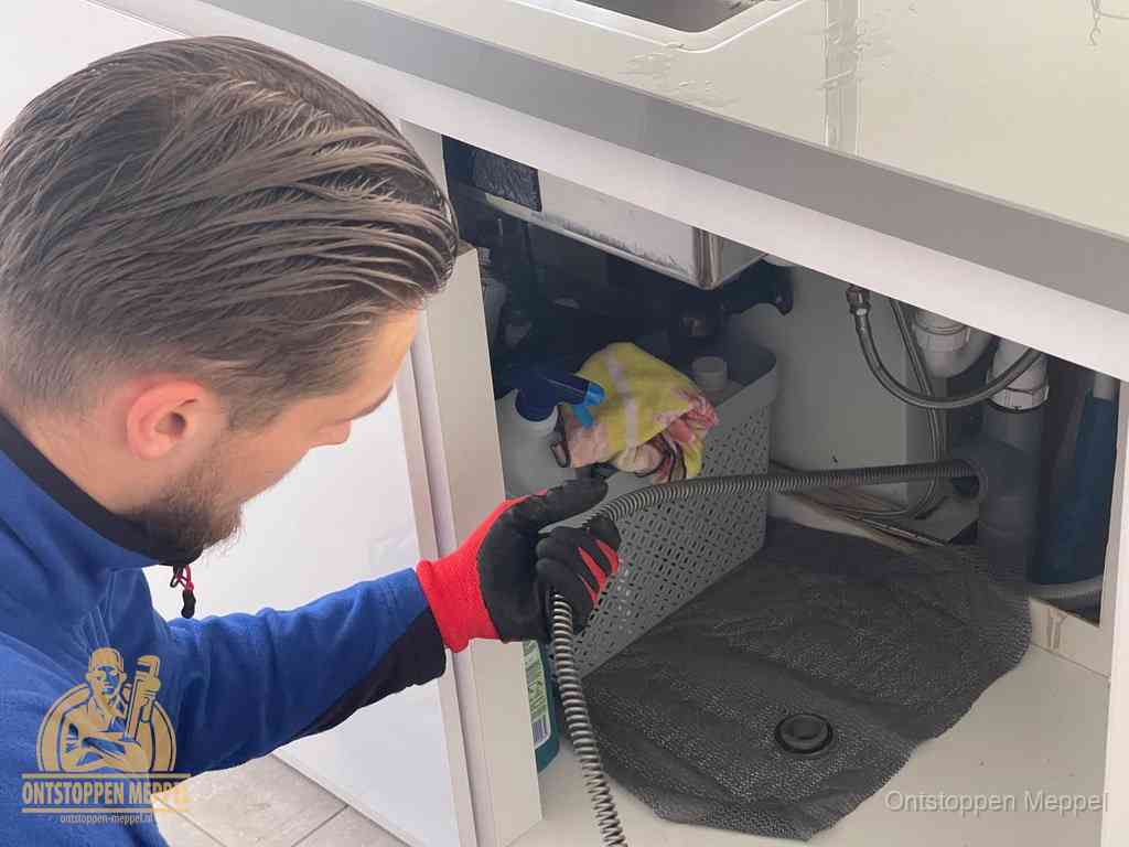 Een monteur voert een flexibele ontstoppingsveer in de afvoer om een verstopping voorbij de bocht van het toilet te bereiken in Meppel Een monteur voert een flexibele ontstoppingsveer in de afvoer om een verstopping voorbij de bocht van het toilet te bereiken in Meppel