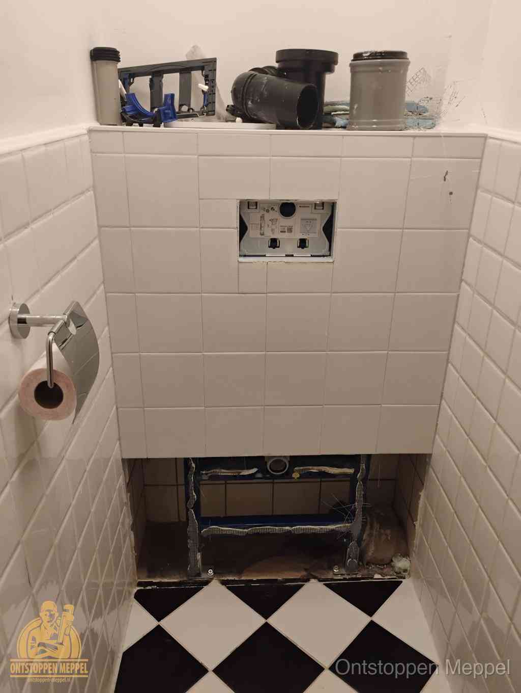 Een toiletruimte waar het hangtoilet en de inbouwreservoir-onderdelen zijn vrijgelegd voor onderhoud, periodiek nazicht voorkomt een wc-verstopping in Meppel Een toiletruimte waar het hangtoilet en de inbouwreservoir-onderdelen zijn vrijgelegd voor onderhoud, periodiek nazicht voorkomt een wc-verstopping in Meppel